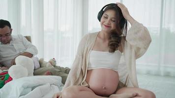 la donna incinta ascolta la musica mentre il marito gioca con la figlia a casa video