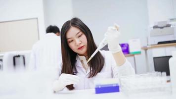 jeune scientifique médicale travaillant dans un laboratoire médical, jeune femme scientifique utilisant une pipette automatique pour transférer un échantillon