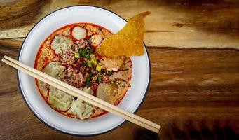 Pork wonton in spicy Tom Yum soup with minced pork and fish ball in white bowl. photo