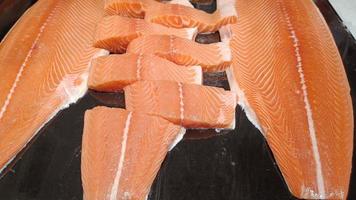 salmón crudo en rodajas en una bandeja negra foto