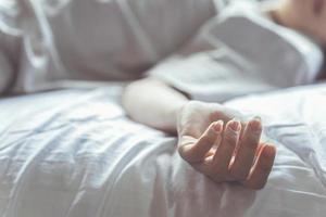 mujer suicidándose en la cama, concéntrese en la mano del cadáver. el concepto de morir solo. foto