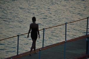 woman in evening at jetty and sea photo