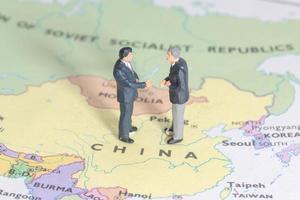 Dos empresarios en miniatura shakehand en el mapa de china