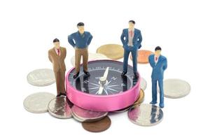 Miniature businessman and compass on coins stack on white background photo