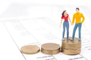 Miniature couple people and stack coins on statement. saving and loan concept. photo