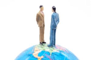 Miniature businessman on the globe on white background photo