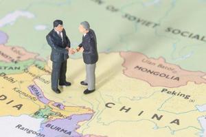 Dos empresarios en miniatura shakehand en el mapa de china foto