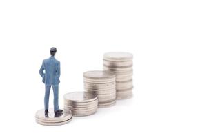 Miniature businessman and coins on white background photo