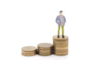 Miniature businessman and coins on white background photo