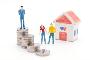 Miniature businessman standing on coins and the house behind. saving and loan concept. photo