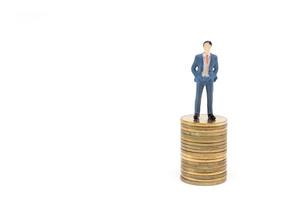 Miniature businessman and coins on white background photo