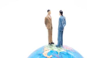 Miniature businessman on the globe on white background photo