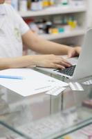 Pharmacist with laptop computer and medication in the pharmacy photo