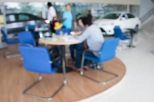 blur photo of car showroom with salesman and customers