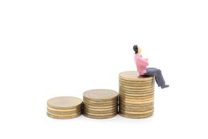 Miniature businessman and coins on white background photo