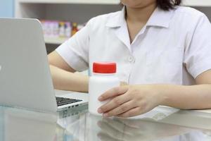 farmacéutico con computadora portátil y medicamentos en la farmacia foto