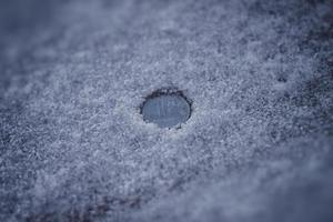 Ruble coin among dirty snow and ashes. photo