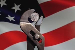 Coin one ruble is clamped in a wrench against the background of the flag of America. The idea of the collapse of the ruble and economy sanctions against Russia. photo