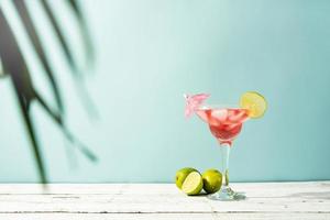 Fresh summer cocktail with strawberry, lime and ice cubes on blue background with copy space photo