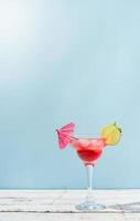 Fresh summer cocktail with strawberry, lime and ice cubes on blue background with copy space photo