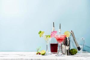 Fresh summer cocktails with strawberry, lime and ice cubes on blue background with copy space photo