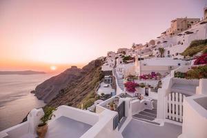 Summer vacation panorama, luxury famous Europe destination. White architecture in Santorini, Greece. Perfect travel scenery with pink flowers and cruise ship in sunlight and blue sky. Amazing view