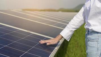 Close up of hand engineer touching with Photovoltaic Cell Farm or Solar Panels Field, eco friendly and clean energy. photo