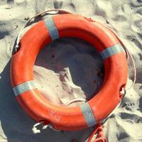 Orange life buoy over sand on the shore photo