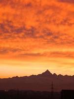 puesta de sol roja con horizonte de nubes y montañas foto