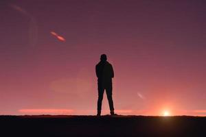 silueta de hombre adulto en la montaña con un romántico fondo de puesta de sol foto