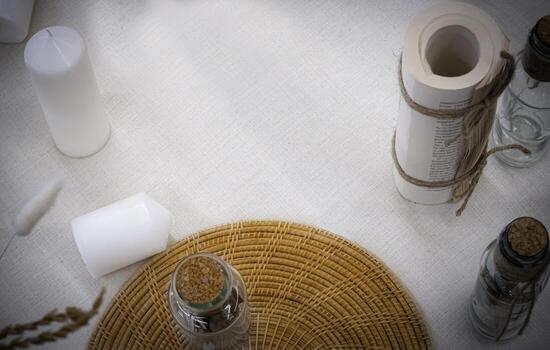 vista superior de la mesa cubierta con calico y vela blanca hay un espacio de copia en blanco en el medio y un rollo de papel impreso. Pon la mesa. organizar en un estilo minimalista. foto