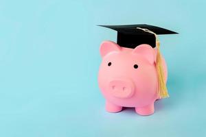 Pink piggy money bank with graduation cap with copy space photo