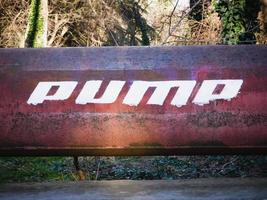 Rusty iron pipe with white text. Word PUMP written on a pipe. photo