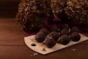 Cocoa balls, chocolate truffles cakes on board on wooden background photo