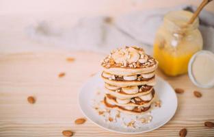 Stack of delicious pancakes with honey, nuts and slices of banana. photo