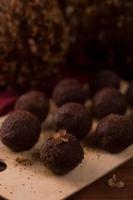 Cocoa balls, chocolate truffles cakes on board on wooden background