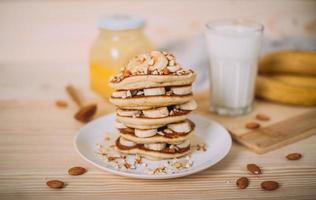 Stack of delicious pancakes with honey, nuts and slices of banana. photo