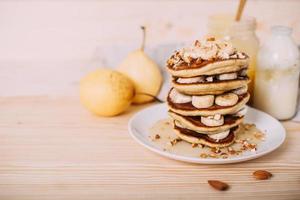 Stack of delicious pancakes with honey, nuts and slices of banana. photo