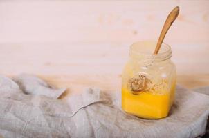 A jar of solid honey and cloth on wooden background. photo