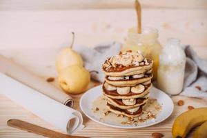 Stack of delicious pancakes with honey, nuts and slices of banana. photo