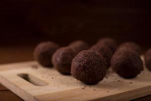 Cocoa balls, chocolate truffles cakes on board on wooden background photo