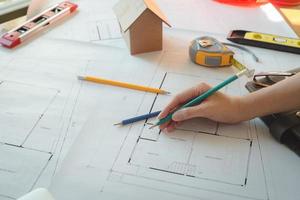 Hands of architect woman or engineer using pencil working with blueprint on desk in office. Engineering tools and construction concept. Architect and Business concept.Teamwork Concept.Vintage effect. photo