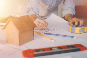 Hands of architect woman or engineer using pencil working with blueprint on desk in office. Engineering tools and construction concept. Architect and Business concept.Teamwork Concept.Vintage effect. photo