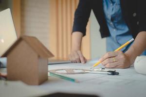 Hands of architect woman or engineer using pencil working with blueprint on desk in office. Engineering tools and construction concept. Architect and Business concept.Teamwork Concept.Vintage effect. photo