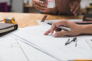 equipo de arquitectos o ingenieros discutiendo en el escritorio con planos sobre el nuevo proyecto de inicio en el escritorio. grupo de equipo en los documentos de verificación del sitio de construcción y el flujo de trabajo comercial. enfoque selectivo. foto