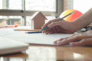 manos de mujer arquitecta o ingeniera usando lápiz trabajando con planos en el escritorio en la oficina. herramientas de ingeniería y concepto de construcción. concepto de arquitecto y negocio. concepto de trabajo en equipo. efecto vintage. foto