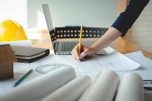 Hands of architect woman or engineer using pencil working with blueprint on desk in office. Engineering tools and construction concept. Architect and Business concept.Teamwork Concept.Vintage effect. photo