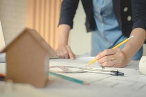 manos de mujer arquitecta o ingeniera usando lápiz trabajando con planos en el escritorio en la oficina. herramientas de ingeniería y concepto de construcción. concepto de arquitecto y negocio. concepto de trabajo en equipo. efecto vintage. foto