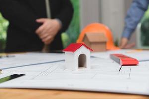 equipo de arquitectos o ingenieros discutiendo en el escritorio con planos sobre el nuevo proyecto de inicio en el escritorio. grupo de equipo en los documentos de verificación del sitio de construcción y el flujo de trabajo comercial. enfoque selectivo. foto