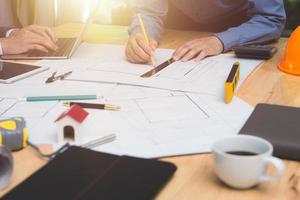 equipo de arquitectos o ingenieros discutiendo en el escritorio con planos sobre el nuevo proyecto de inicio en el escritorio. grupo de equipo en los documentos de verificación del sitio de construcción y el flujo de trabajo comercial. enfoque selectivo. foto